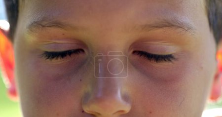 Téléchargez les photos : Le visage du garçon ferme les yeux de près. macro-yeux d'enfant avec les yeux fermés dans la méditation et la contemplation - en image libre de droit