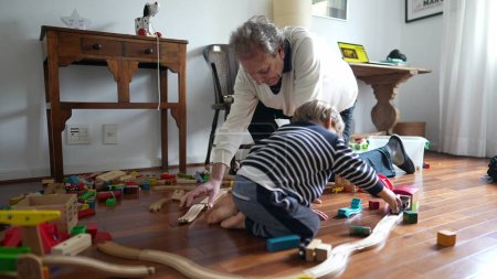 Photo for Grandfather and Grandson Bonding on Bedroom Floor, Authentic Moment Between Elderly Man and Grandchild Playing - Royalty Free Image