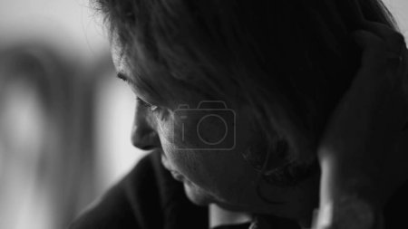 Photo for Monochromatic Elderly woman deeply engrossed in thought, close-up showcasing her intent focus as she leans forward seeking answers, black and white - Royalty Free Image