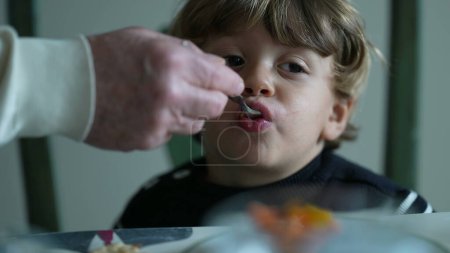 Foto de Alimentación con la mano a un niño pequeño, primer plano de un niño caucásico comiendo fruta - Imagen libre de derechos