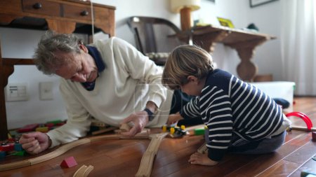 Téléchargez les photos : Ensemble de train de construction pour hommes et jeunes garçons âgés sur plancher en bois, grand-père et petit-fils attachant du temps ensemble - en image libre de droit