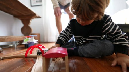 Foto de Niño jugando con coches de juguete en suelo de madera - Imagen libre de derechos