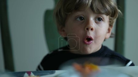 Téléchargez les photos : Nourrir à la main un petit garçon, gros plan sur le visage d'un enfant caucasien mangeant des fruits - en image libre de droit
