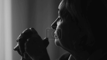 Foto de Mujer anciana monocromática profundamente absorta en el pensamiento, de cerca mostrando su intención de enfoque mientras se inclina hacia adelante en busca de respuestas, en blanco y negro - Imagen libre de derechos