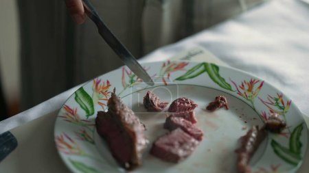 Foto de Primer plano cortar a mano trozos de carne en el plato, persona sosteniendo cuchillo y tenedor en rodajas filete comer comida de almuerzo - Imagen libre de derechos