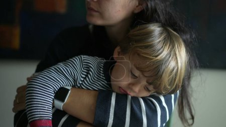Foto de Escena conmovedora de madre abrazando al niño, auténtico momento de estilo de vida maternal de mamá sosteniendo a un niño pequeño en brazos dando calidez y cuidado - Imagen libre de derechos