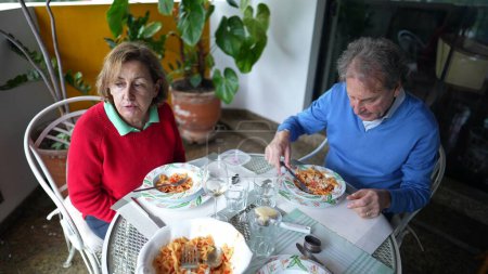 Foto de Pareja de ancianos disfrutando del almuerzo en el apartamento Balcón, marido y mujer jubilados compartiendo momentos de comida en la terraza juntos, estilo de vida doméstico escena de la vejez - Imagen libre de derechos