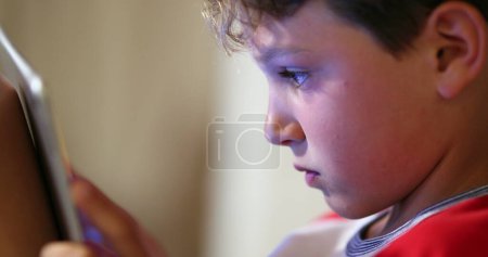 Foto de Niño sosteniendo la tableta. Niño nativo digital usando dispositivo de tecnología de pantalla táctil jugando videojuego, navegando por Internet - Imagen libre de derechos