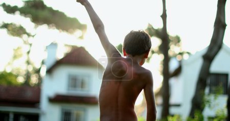 Photo for Confident child celebrating success by raising fists in the air. Boy raises arms in the sky in celebration - Royalty Free Image