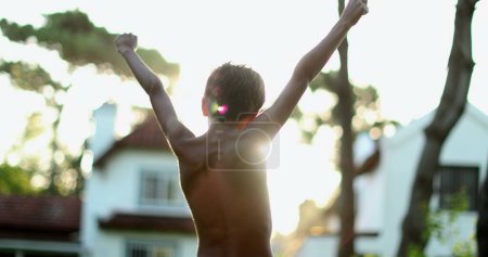 Téléchargez les photos : Confident child celebrating success by raising fists in the air. Boy raises arms in the sky in celebration - en image libre de droit