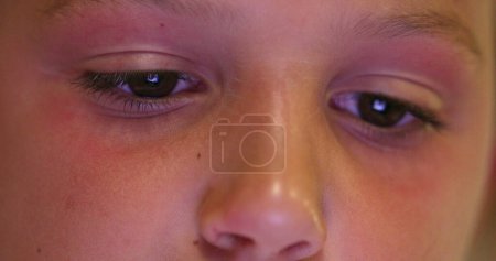 Téléchargez les photos : Child eyes staring at screen device, kid using tablet playing game online. Close-up of boy eye watching content - en image libre de droit