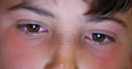 Téléchargez les photos : Child boy eyes looking at tablet device screen. Kid staring at blue light macro eye close-up - en image libre de droit