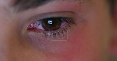 Téléchargez les photos : Child eyes looking at device screen. Young boy red eye staring at blue light glow at night - en image libre de droit