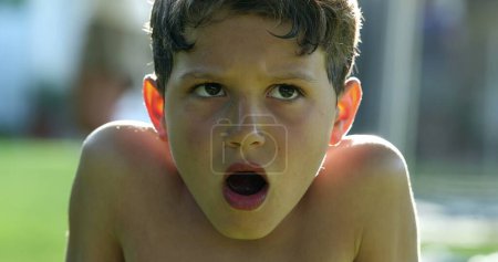 Foto de Concerned pensive child boy thinking outside with mouth open in shock - Imagen libre de derechos