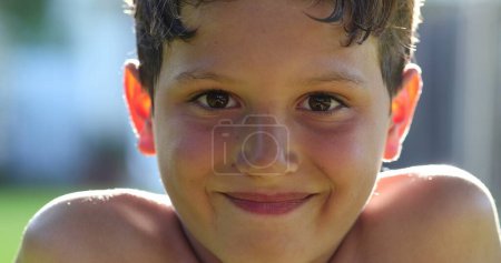 Photo for Handsome child boy face portrait smiling to camera outside in sunlight. Kid closing and opening eyes feeling happy and smiling - Royalty Free Image