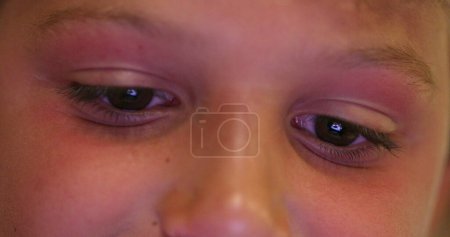 Téléchargez les photos : Child eyes staring at screen device, kid using tablet playing game online. Close-up of boy eye watching content - en image libre de droit