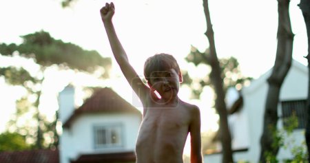 Photo for Child in victory stand raising fist in the air celebrating achievement and success with arm raised to the sky - Royalty Free Image