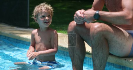 Photo for Father teaching toddler boy to swim. Dad educating theoretical swim technique to toddler boy. Child asking question to parent - Royalty Free Image