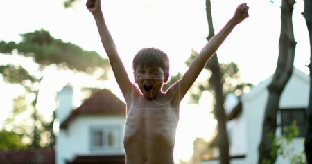 Téléchargez les photos : Child celebrating success and achievement by raising arm in the air. Young boy raises arms and fists in the sky - en image libre de droit