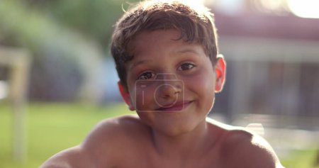 Foto de Handsome child boy smiling to camera in outdoor backyard garden. Happy kid portrait - Imagen libre de derechos