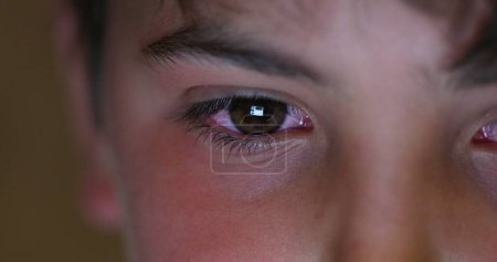 Foto de Ojos de niño mirando a la pantalla por la noche. Primer plano de la cara del niño mirando el dispositivo de la tableta - Imagen libre de derechos