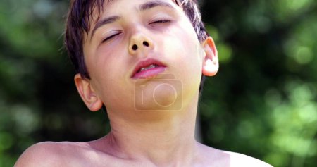 Téléchargez les photos : Portrait of young boy taking a deep breath outside. Meditative child resting and relaxing outside - en image libre de droit