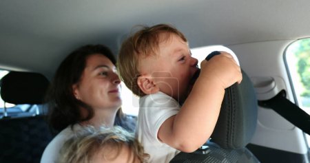 Photo for Mother holding baby infant in backseat car without security prevention, crying upset toddler - Royalty Free Image