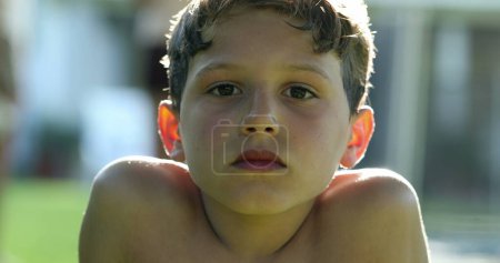 Téléchargez les photos : Pensive boy thinking outside in sunlight. Child looking to camera portrait face serious - en image libre de droit