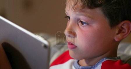 Téléchargez les photos : Jeune garçon jouant jeu en ligne avec tablette tech. Addiction des enfants au jeu vidéo en compétition. Technologie génération indigène - en image libre de droit
