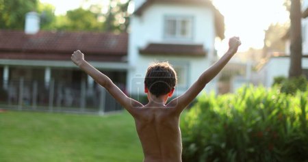 Téléchargez les photos : Kid raising arms in the air. Young boy child in victory stand raises fist outside - en image libre de droit