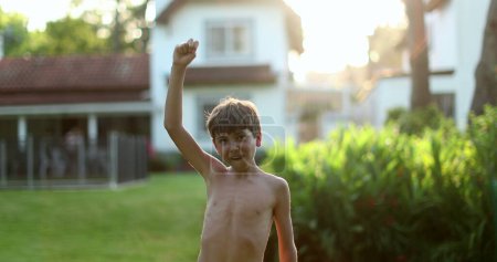 Téléchargez les photos : Jeune garçon levant le bras dans l'air pour célébrer à l'extérieur - en image libre de droit