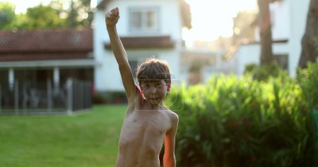 Téléchargez les photos : Jeune garçon levant le bras dans l'air pour célébrer à l'extérieur - en image libre de droit