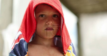 Téléchargez les photos : Pensive child boy wrapped with towel after swimming at the pool. Thoughtful kid drying body - en image libre de droit