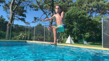 Foto de Niño corriendo y saltando al agua de la piscina durante el día de verano - Imagen libre de derechos