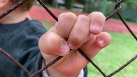 Téléchargez les photos : Closeup of baby little hand holding fence - en image libre de droit