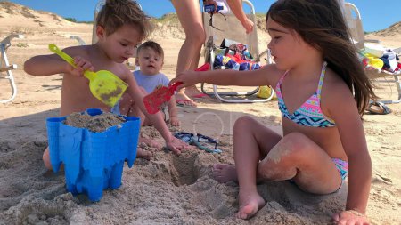 Foto de Niños en la playa jugando con arena, niños haciendo castillo de arena durante las vacaciones de verano - Imagen libre de derechos