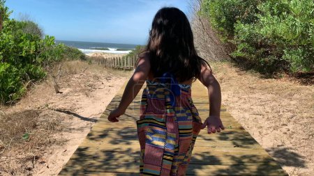 Téléchargez les photos : Enfant fille marche vers la plage sur la route de chemin de rive - en image libre de droit