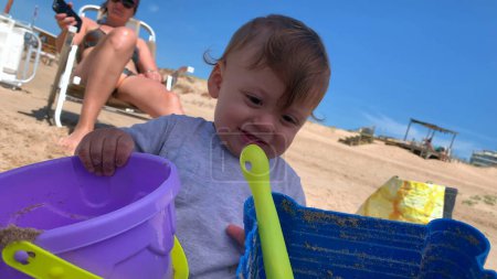 Foto de Bebé jugando en la playa, niño pequeño juega con cubos y pala - Imagen libre de derechos