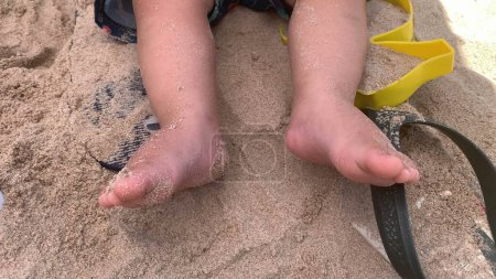 Téléchargez les photos : Bébé pieds de bébé à la plage. Pied nu pied de bambin assis dans le sable - en image libre de droit