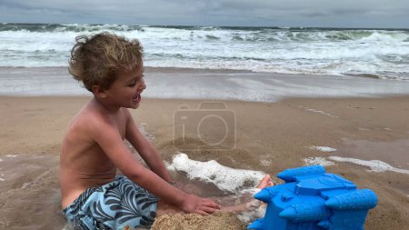 Photo for Cute infant child playing at beach shore feeling happy, enjoying vacations - Royalty Free Image