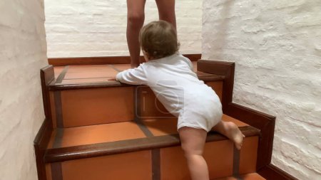 Foto de Active cute baby infant climbing home stairs, sibling blocking toddler - Imagen libre de derechos