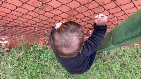 Téléchargez les photos : Baby hands holding into wire fence - en image libre de droit