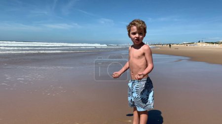 Foto de Niño niño feliz en la playa saltando arriba y abajo extático - Imagen libre de derechos