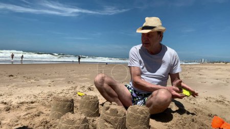 Téléchargez les photos : Grand-père avec des enfants à la plage bâtiment Sandcastle - en image libre de droit