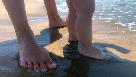 Téléchargez les photos : Bébé mignon à la plage. Adorable bébé heureux tout-petit pieds et orteils sentir l'eau - en image libre de droit