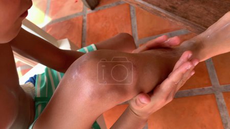 Foto de Kid propagación de crema solar a la pierna - Imagen libre de derechos