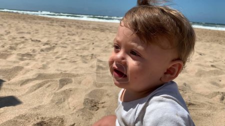 Téléchargez les photos : Bébé bébé à la plage sentant le sable avec les orteils et les pieds nus - en image libre de droit