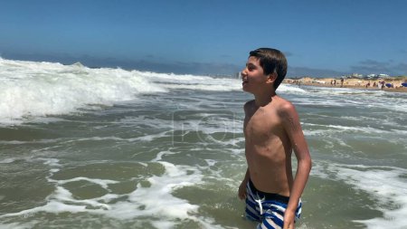 Téléchargez les photos : Garçon jouant avec des vagues de plage plongeant dans l'eau en mer - en image libre de droit