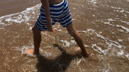 Téléchargez les photos : Pieds d'enfant marchant sur la plage - en image libre de droit