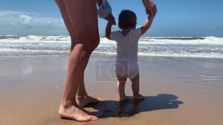 Photo for Mother and baby at beach looking at horizon standing - Royalty Free Image